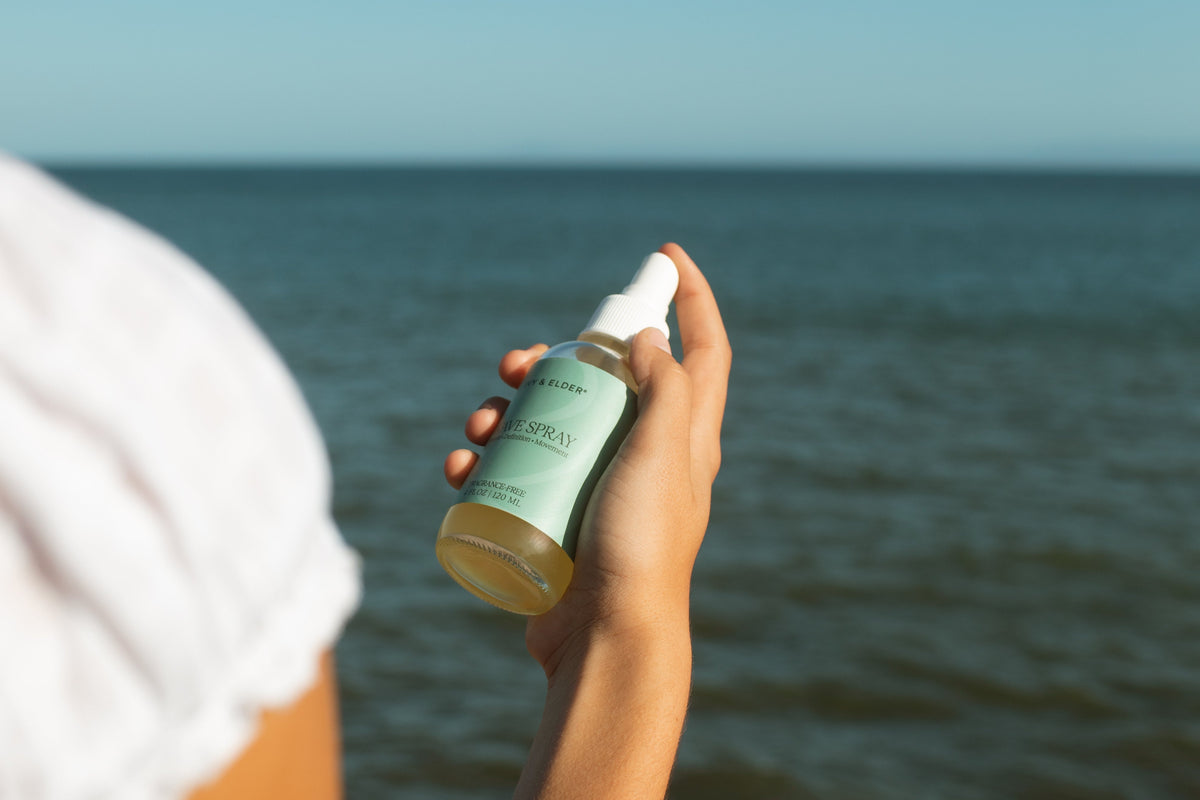 Woman holding wave spray with ocean in background